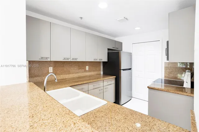 a kitchen with granite countertop a refrigerator and a sink