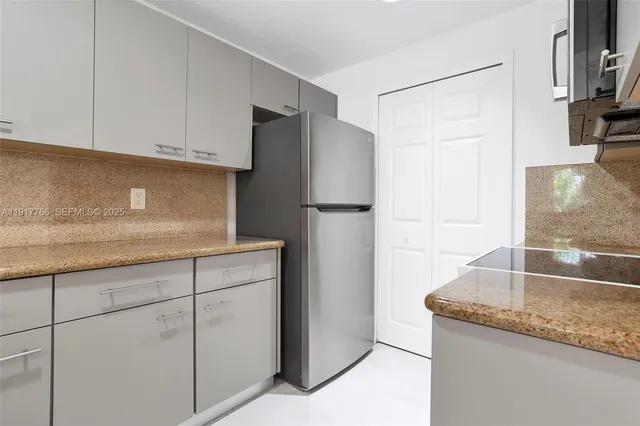 a kitchen with granite countertop a refrigerator and a sink