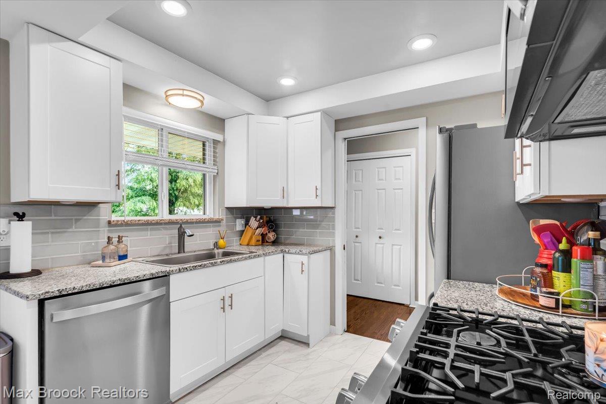 28403 Peppermill Road Farmington, MI 48331 - Photo 12 of 33 Kitchen featuring white cabinetry, granite countertops, stainless steel appliances, subway tile backsplash, and recessed lighting