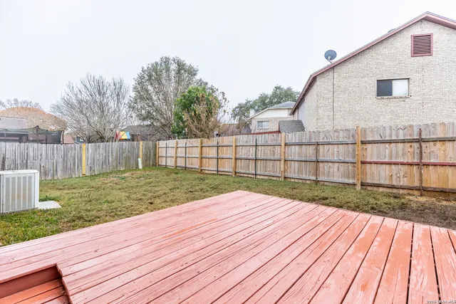 a view of backyard with wooden floor and fence