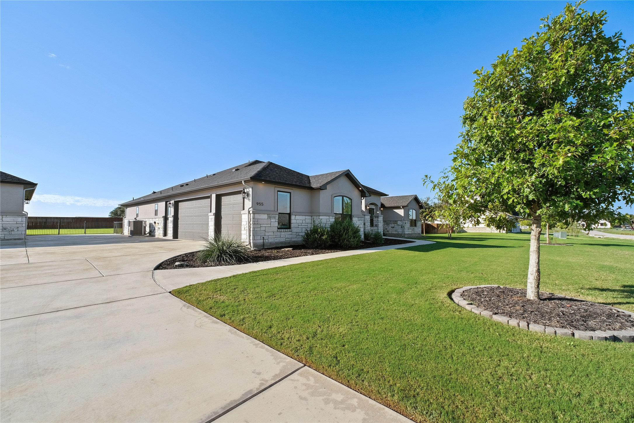 955 Inka Road Salado, TX 76571 - Photo 38 of 39 An expansive concrete driveway leads past the multi-car garage toward a manicured green lawn.