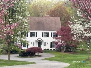 a view of a white house with a yard plants and large tree