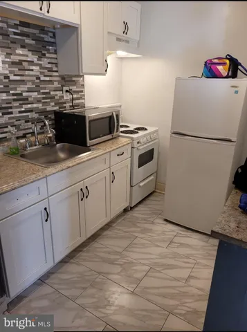 a kitchen with a refrigerator sink and white cabinets