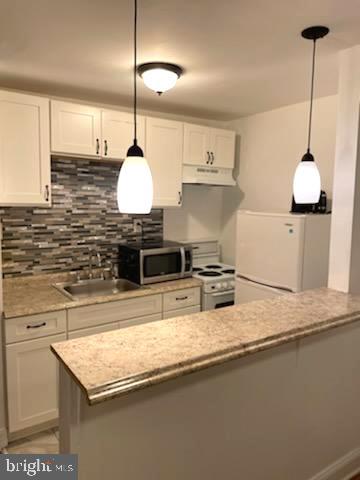 2053 South Cecil Street, Unit 1 Philadelphia, PA 19143 - Photo 5 of 13 a kitchen with stainless steel appliances granite countertop a sink a stove and a wooden floor