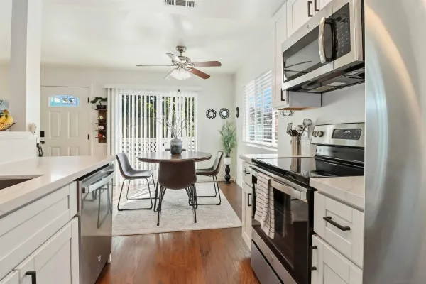 a kitchen with stainless steel appliances granite countertop a stove top oven a sink dishwasher a dining table and chairs with wooden floor