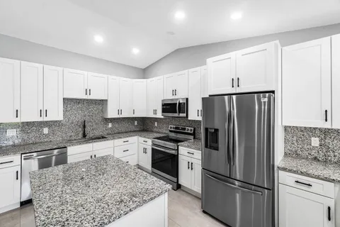 a kitchen with stainless steel appliances granite countertop a refrigerator stove microwave and sink
