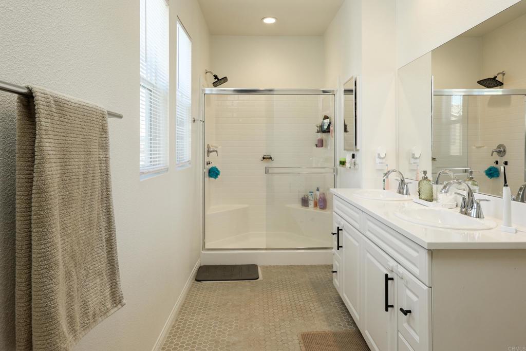 10443 Graphite Street Spring Valley, CA 91977 - Photo 7 of 18 a bathroom with a double vanity sink a mirror a shower and a bathtub