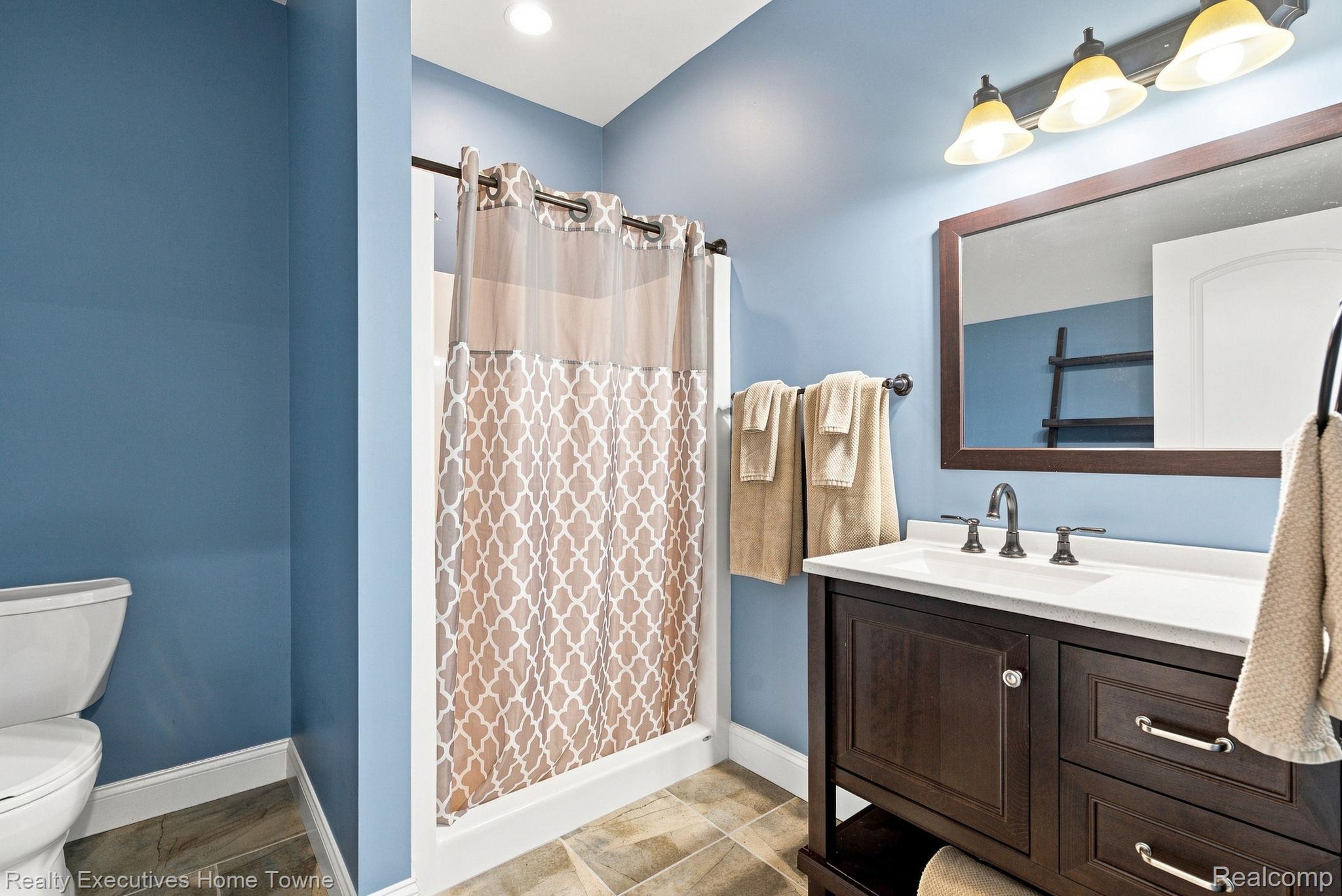 2829 Riverside Drive Port Huron, MI 48060 - Photo 34 of 99 Vanity with a white countertop and dark wood-finish cabinetry, a framed mirror, and a three-light fixture