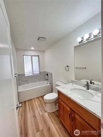 a bathroom with a sink a toilet a mirror and bathtub