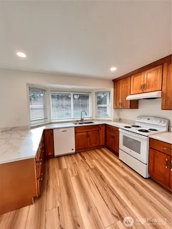 a large kitchen with stainless steel appliances granite countertop a stove a sink dishwasher and a oven with white cabinets