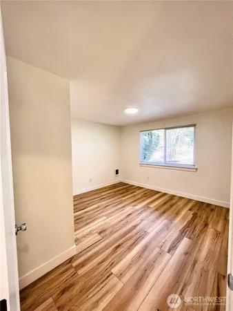 a view of empty room with wooden floor and fan