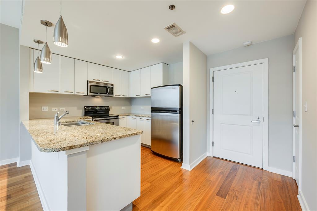 1200 Main Street, Unit 1002 Dallas, TX 75202 - Photo 2 of 30 a kitchen with a refrigerator a sink dishwasher a stove with wooden floor and cabinets