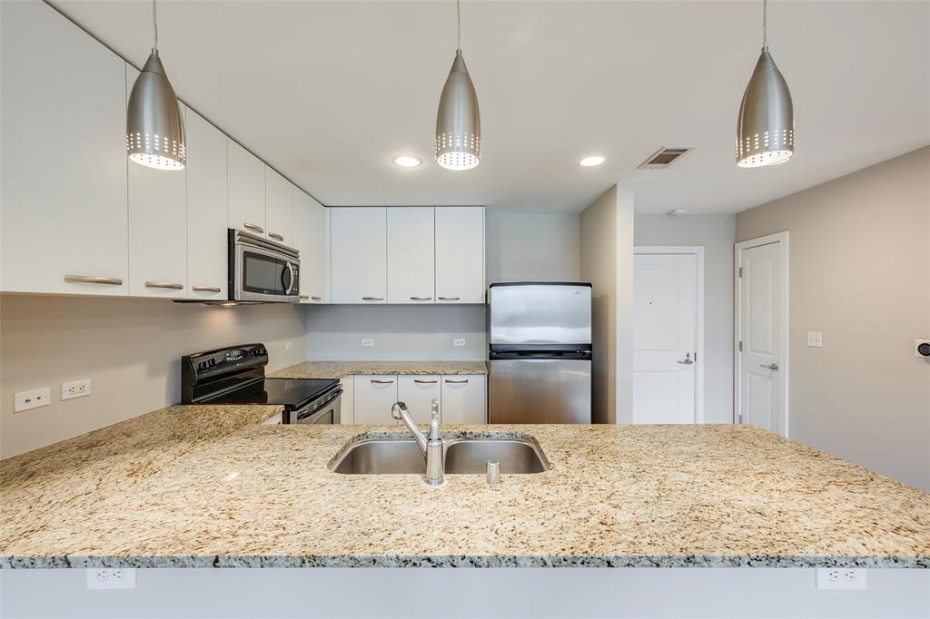 1200 Main Street, Unit 1002 Dallas, TX 75202 - Photo 4 of 30 a kitchen with stainless steel appliances granite countertop a sink refrigerator and cabinets