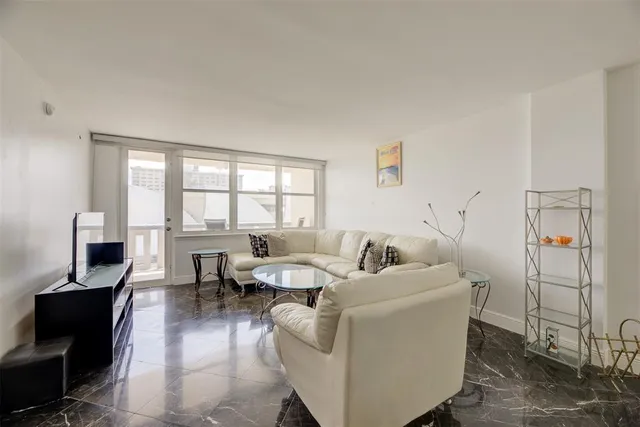 a living room with furniture a flat screen tv and a floor to ceiling window