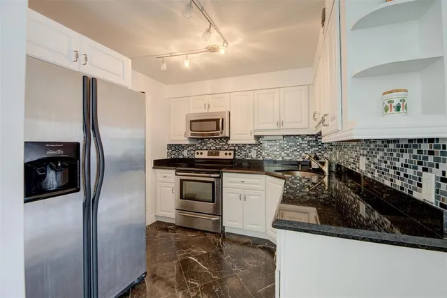 a kitchen with granite countertop a refrigerator stove and microwave