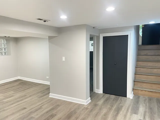 an empty room with wooden floor & windows bathroom