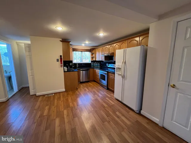 a kitchen with a refrigerator a sink and wooden floor