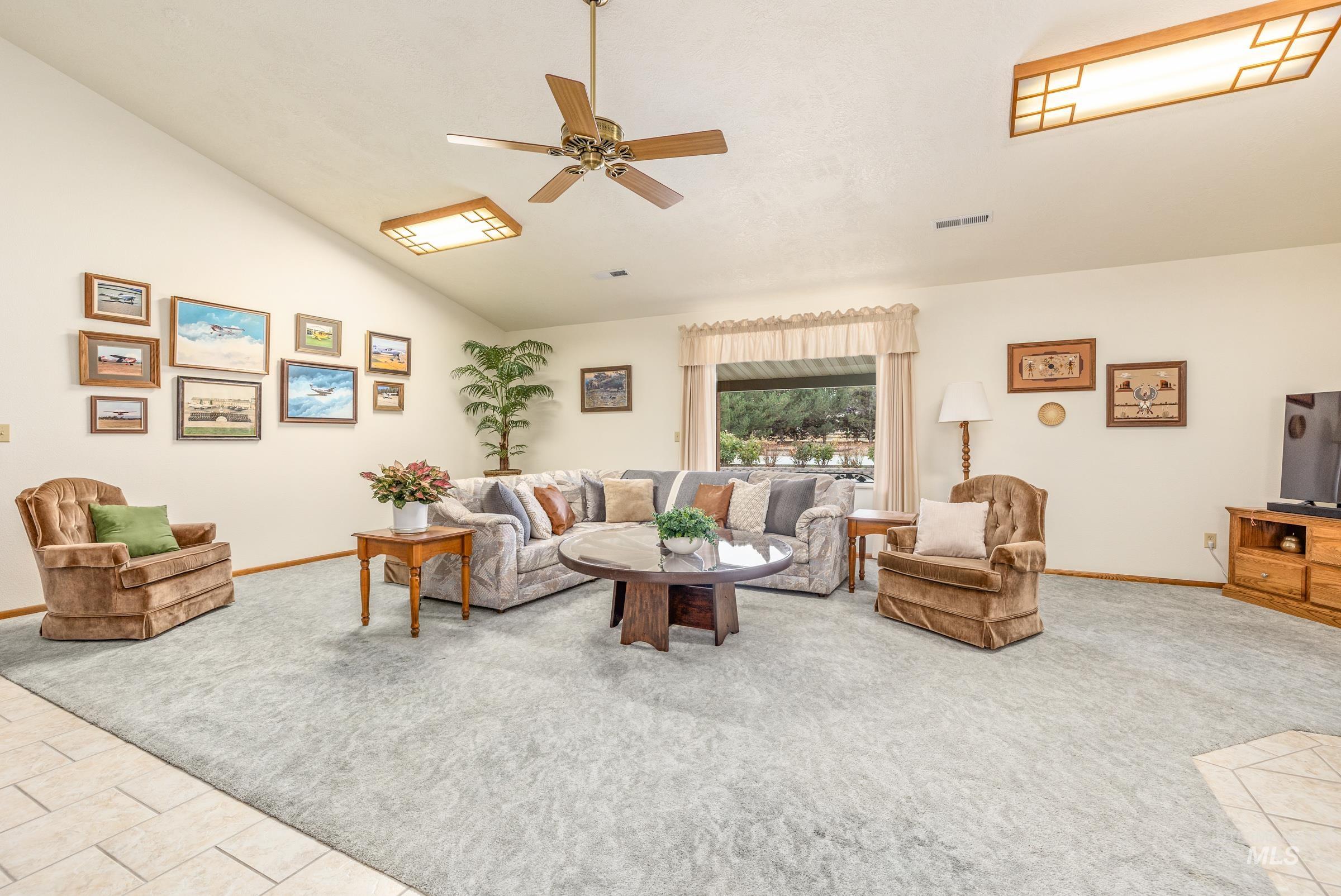 10514 Airpark Loop Road Melba, ID 83641 - Photo 16 of 47 Living area featuring lofted ceiling, ceiling fan, light colored carpet, and light tile patterned flooring
