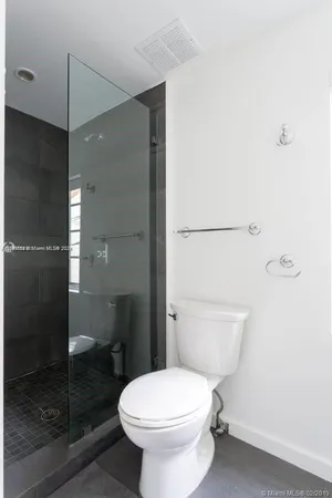 a white toilet sitting next to a bathroom sink and a shower