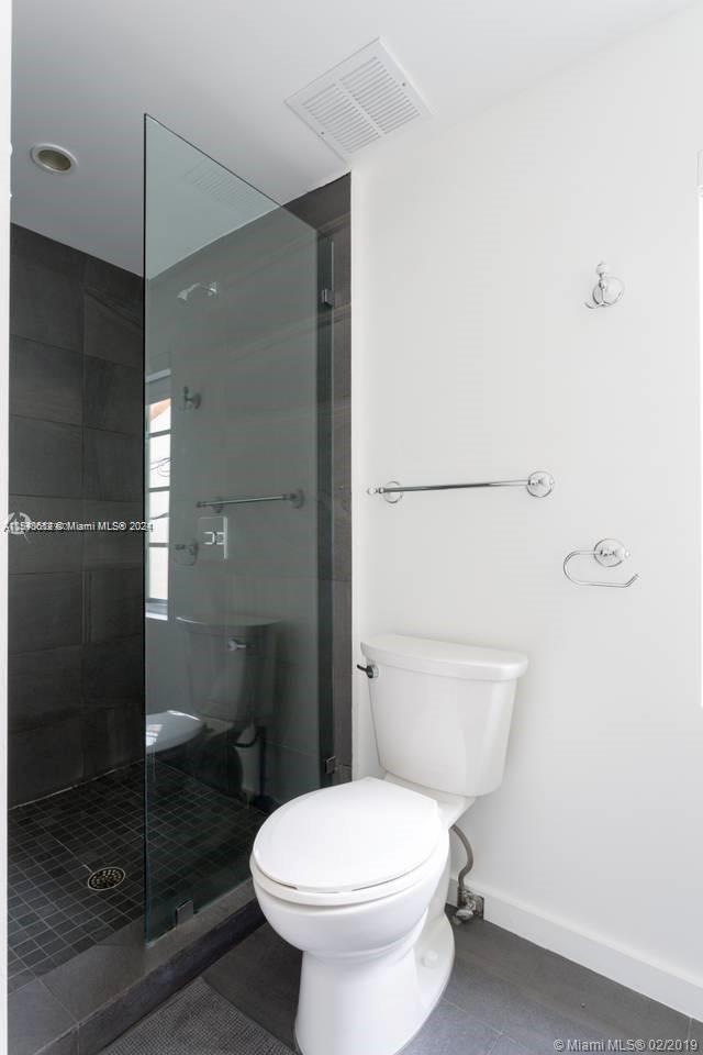 1450 Meridian Avenue, Unit 201 Miami Beach, FL 33139 - Photo 17 of 19 a white toilet sitting next to a bathroom sink and a shower