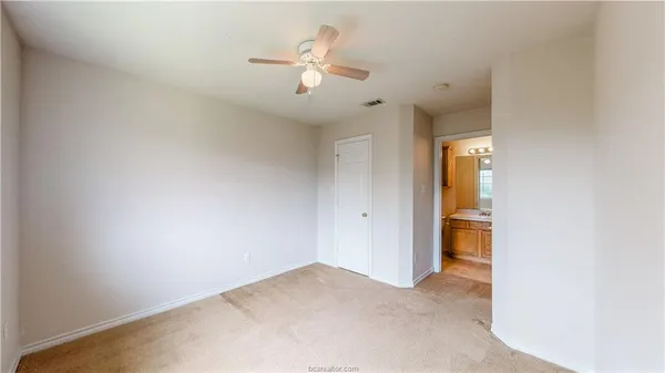 an empty room with a ceiling fan and carpet