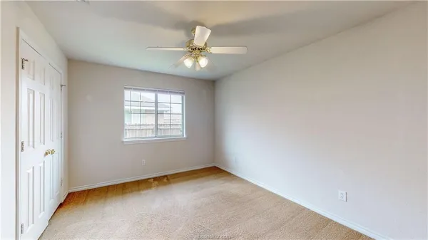 an empty room with a window and a fan
