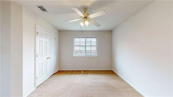 an empty room with a ceiling fan and window