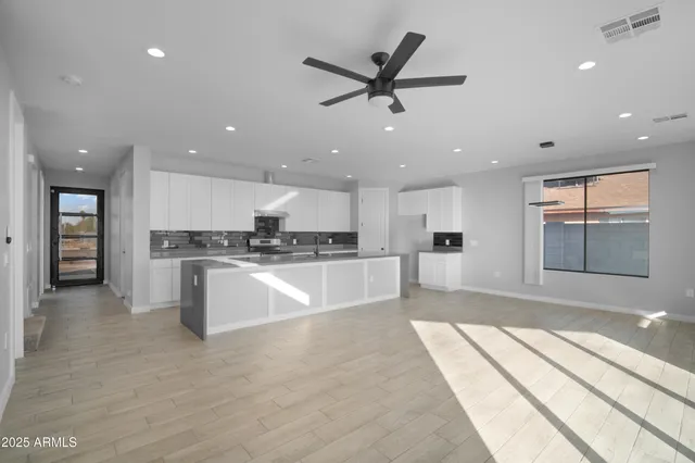 a large white kitchen with kitchen island a sink stainless steel appliances and cabinets