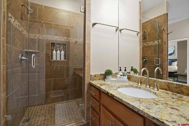 a bathroom with a granite countertop shower a sink and mirror