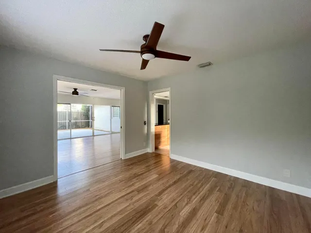 a view of empty room with wooden floor and fan