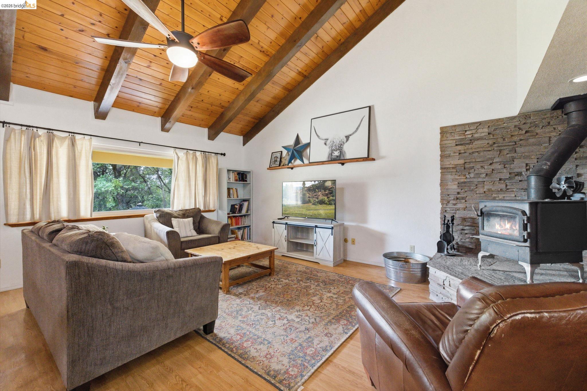16860 Buckhorn Mountain Road Sonora, CA 95370 - Photo 25 of 46 Living area featuring light wood-style floors, ceiling fan, a high wood beamed ceiling, and a wood stove