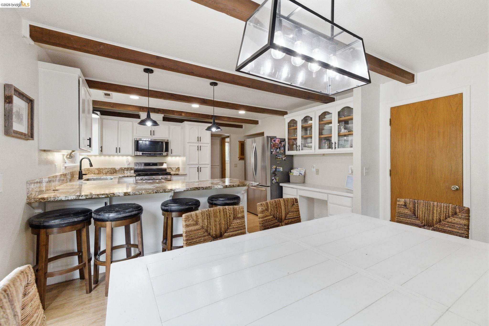 16860 Buckhorn Mountain Road Sonora, CA 95370 - Photo 29 of 46 Kitchen featuring white cabinets, stainless steel appliances, a breakfast bar area, a peninsula, and light stone counters