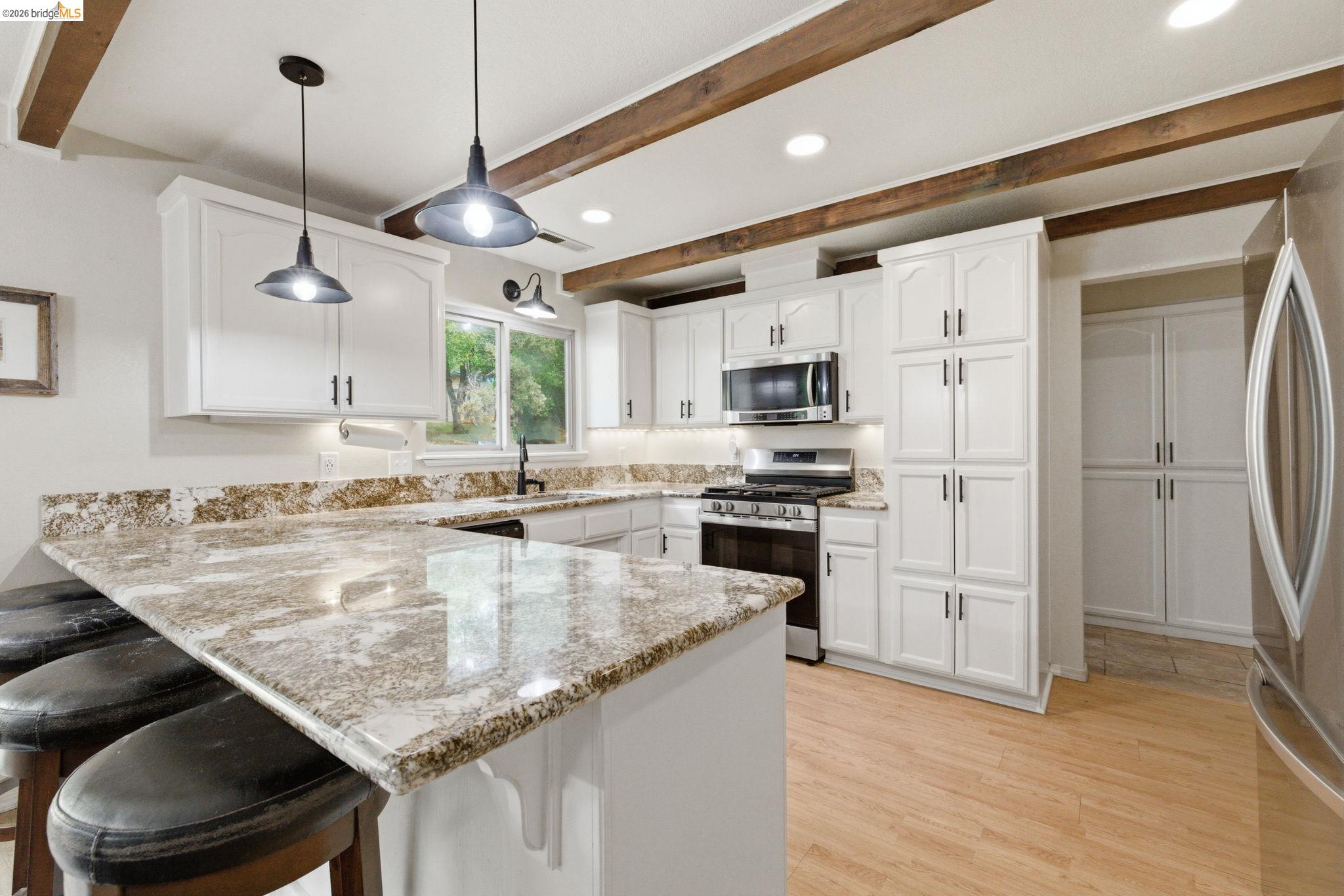16860 Buckhorn Mountain Road Sonora, CA 95370 - Photo 30 of 46 Kitchen featuring a peninsula, a breakfast bar, hanging light fixtures, stainless steel appliances, and white cabinets