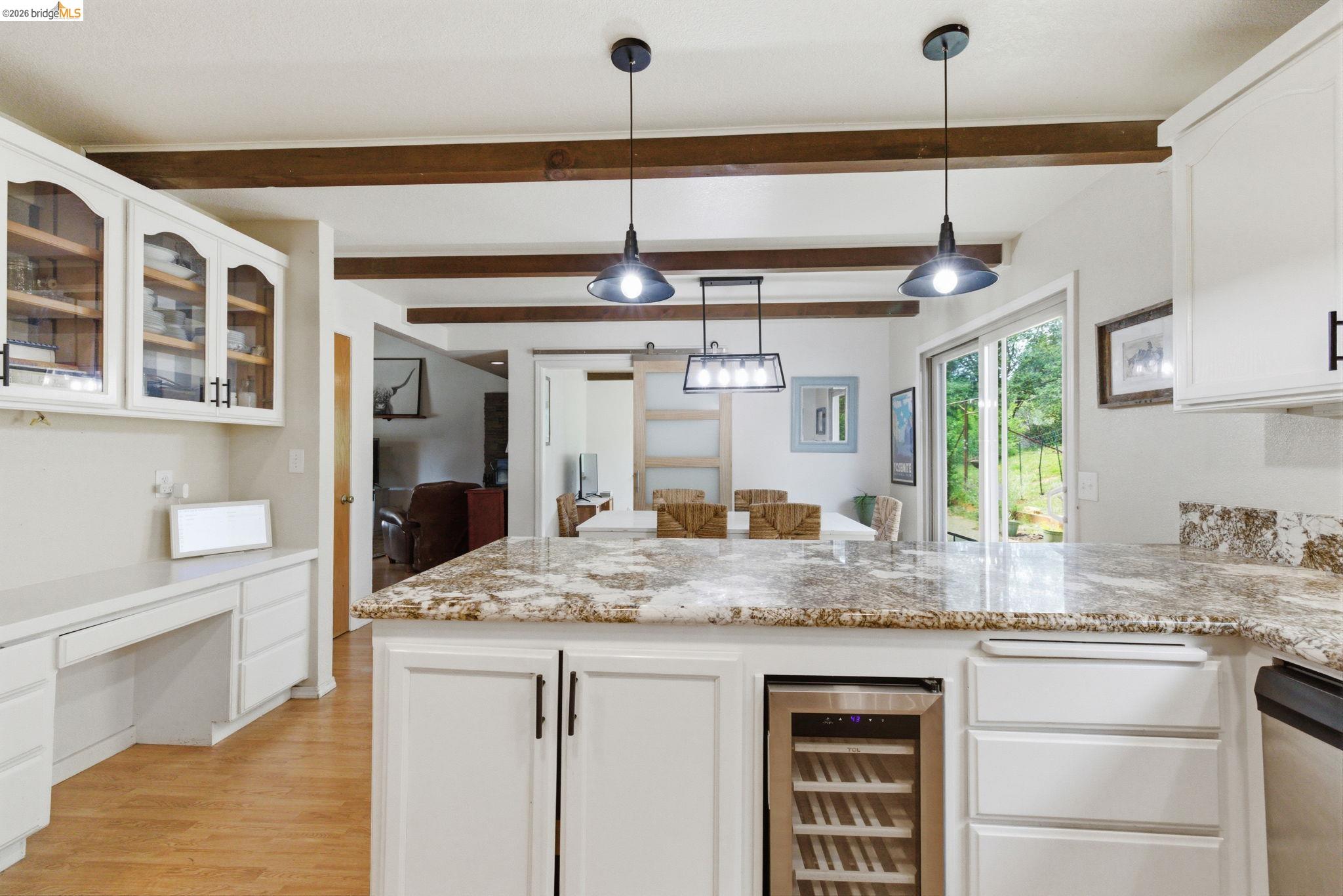 16860 Buckhorn Mountain Road Sonora, CA 95370 - Photo 32 of 46 Kitchen with white cabinets, a peninsula, beverage cooler, light stone counters, and decorative light fixtures