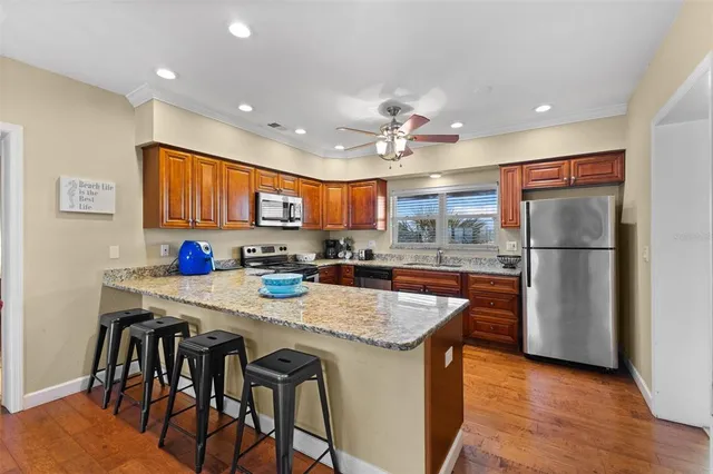 a kitchen with stainless steel appliances granite countertop a table chairs sink refrigerator and cabinets