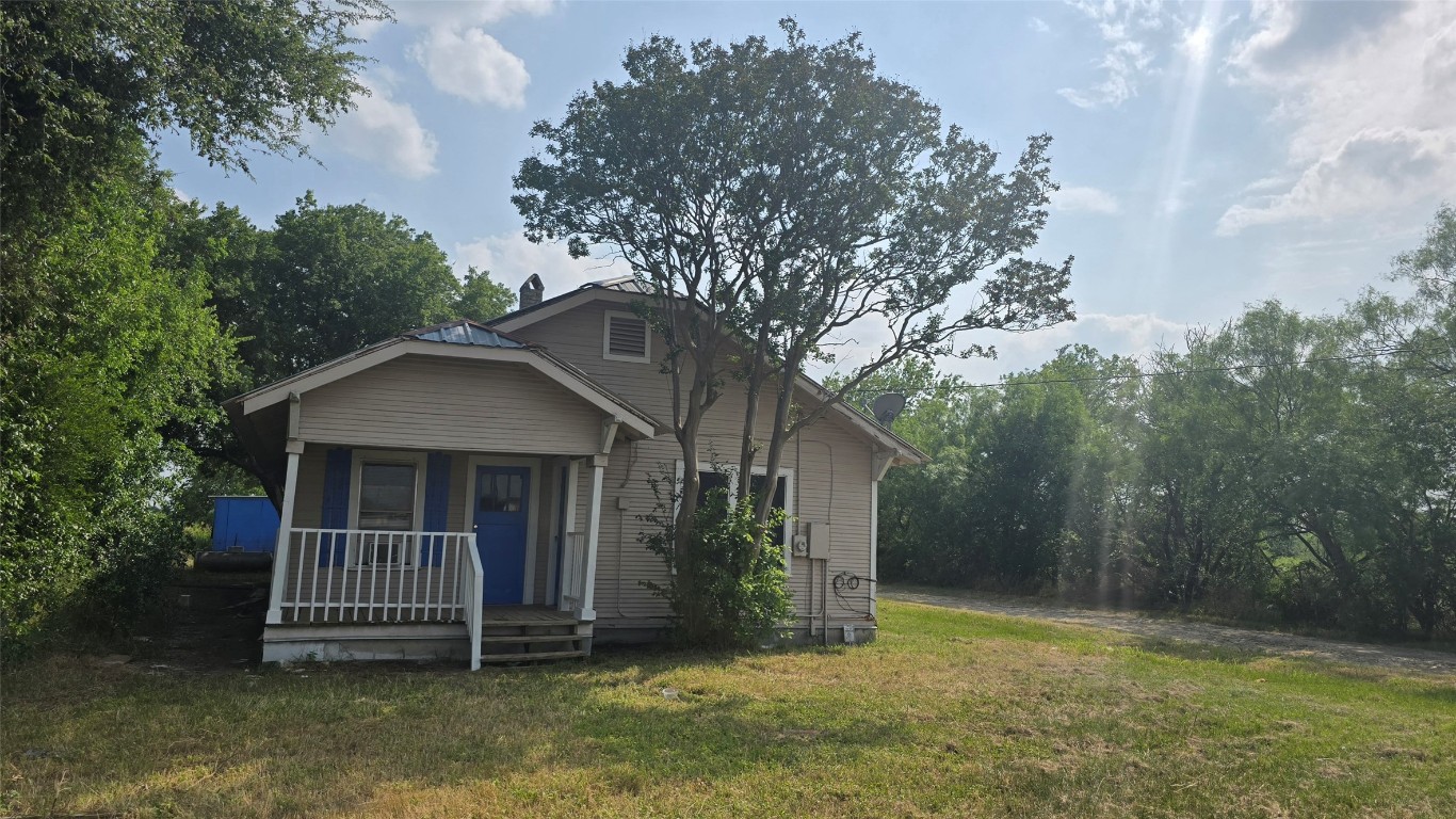 a view of house with a yard and large tree