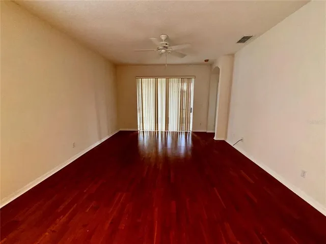 a view of an empty room with wooden floor and a window