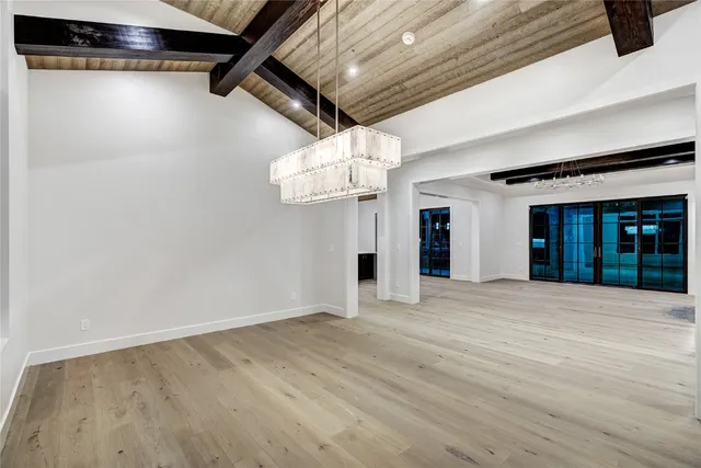 a view of an empty room with chandelier fan and windows