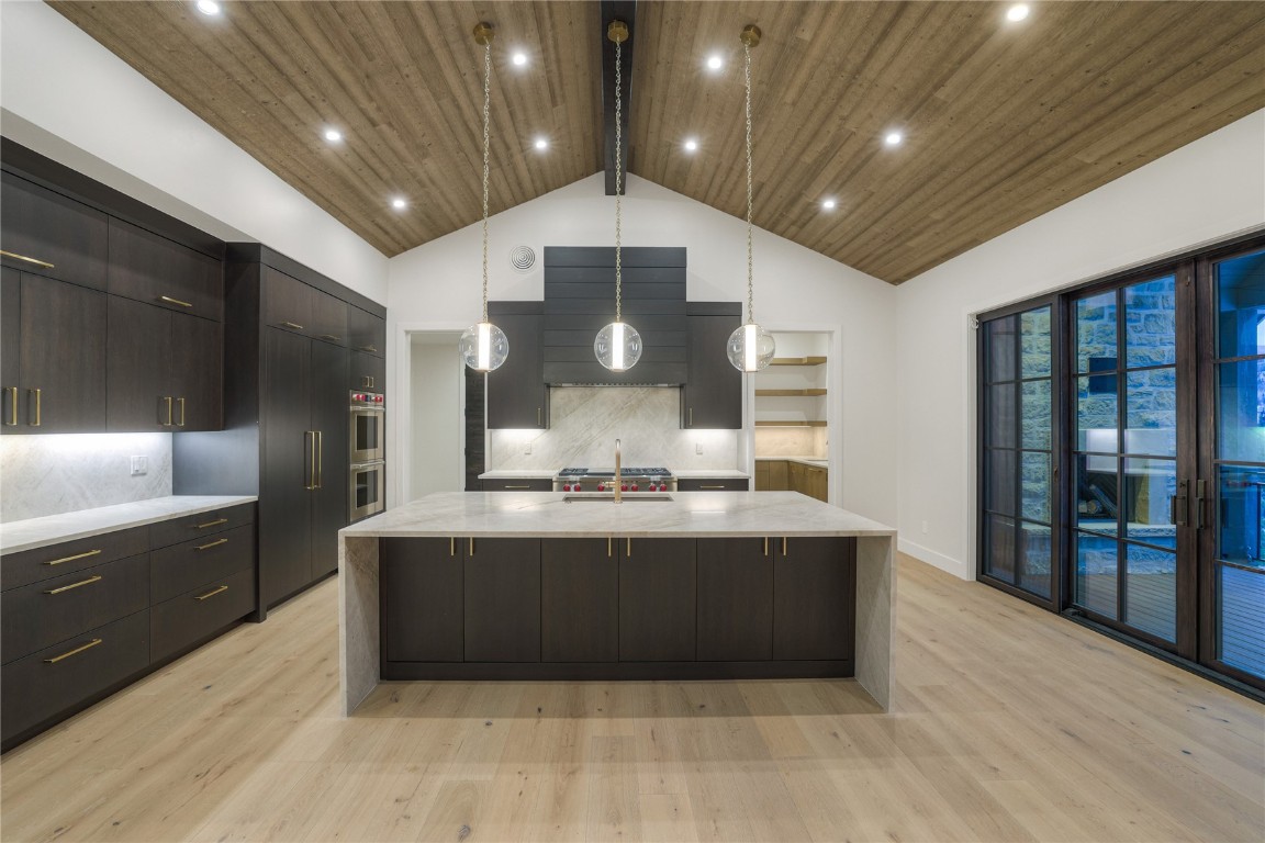 90 West Trade Court Keystone, CO 80435 - Photo 19 of 50 Kitchen featuring modern cabinets, pendant lighting, backsplash, light stone countertops, and a large island with sink