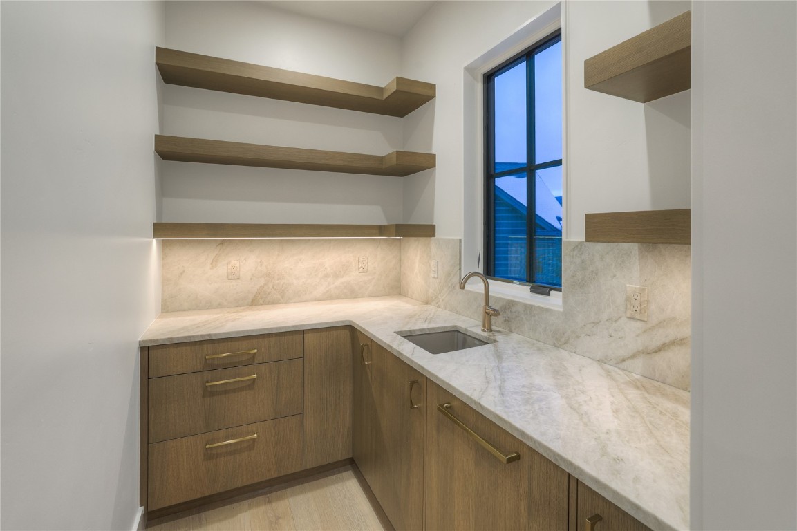 90 West Trade Court Keystone, CO 80435 - Photo 22 of 50 Kitchen with tasteful backsplash, light stone countertops, open shelves, brown cabinetry, and modern cabinets