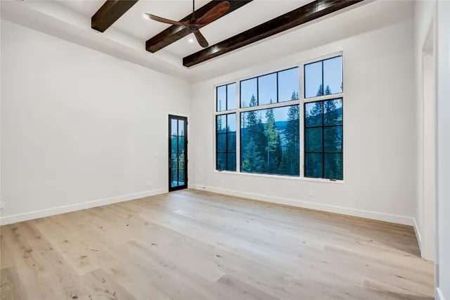 an empty room with wooden floor fan and windows