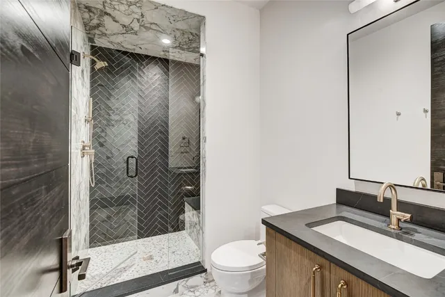 a bathroom with a granite countertop sink a toilet and shower