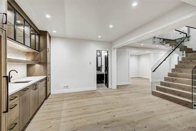 a view of an empty room with wooden floor and stairs