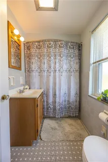 a bathroom with a granite countertop sink a toilet a mirror and shower