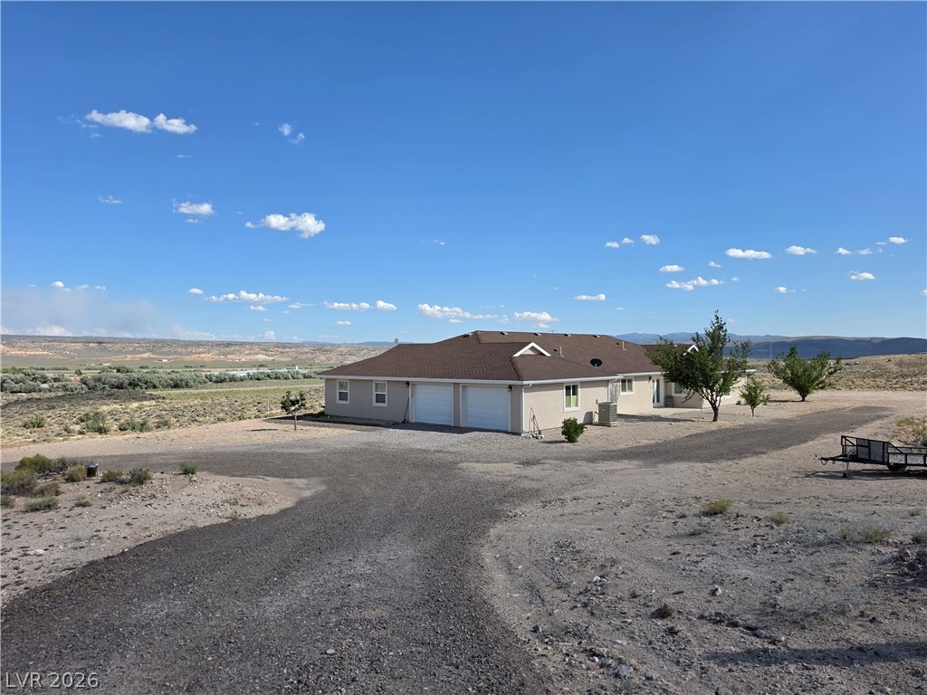 5272 Truman Lane Caliente, NV 89008 - Photo 34 of 43 A spacious desert home with a private driveway and attached garage, offering serene views of the surrounding landscape.