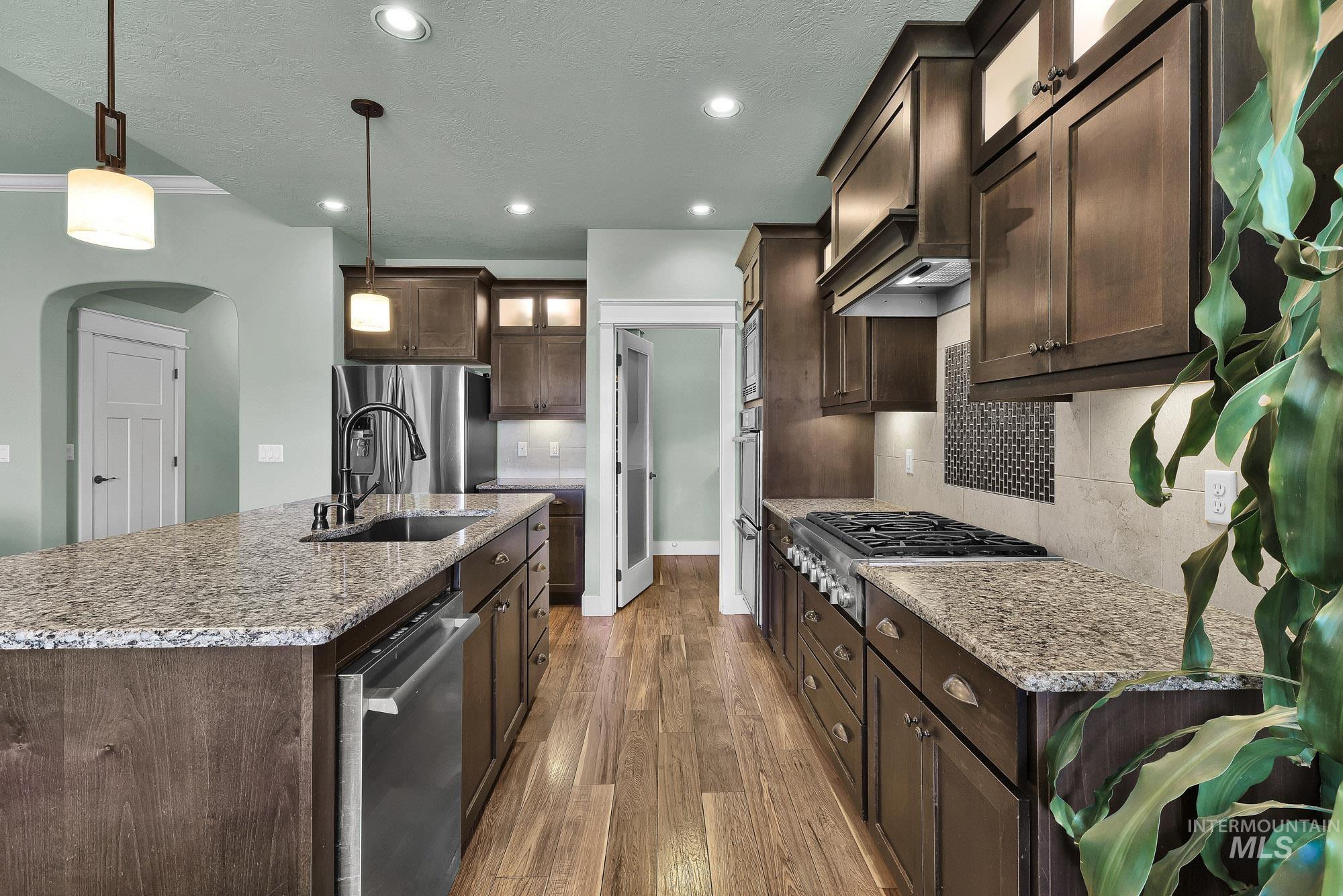 220 South Wildgrass Way Star, ID 83669 - Photo 12 of 50 Kitchen featuring stainless steel appliances, dark wood cabinetry, and granite countertops
