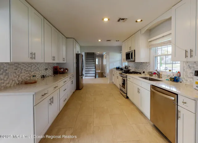 a large kitchen with stainless steel appliances granite countertop a sink and cabinets
