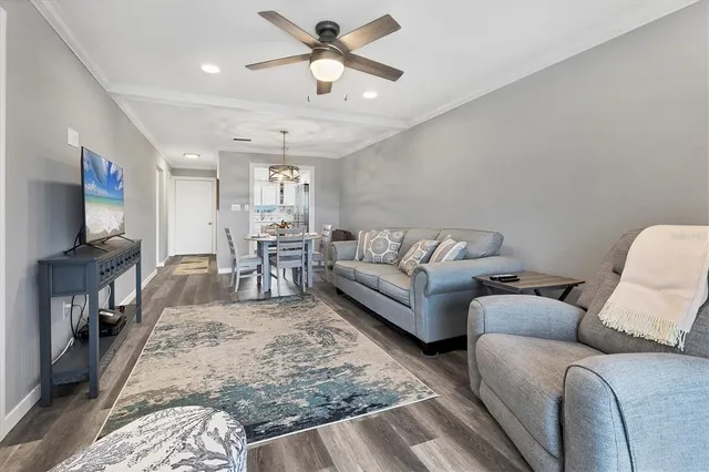 a living room with furniture and a flat screen tv with kitchen view