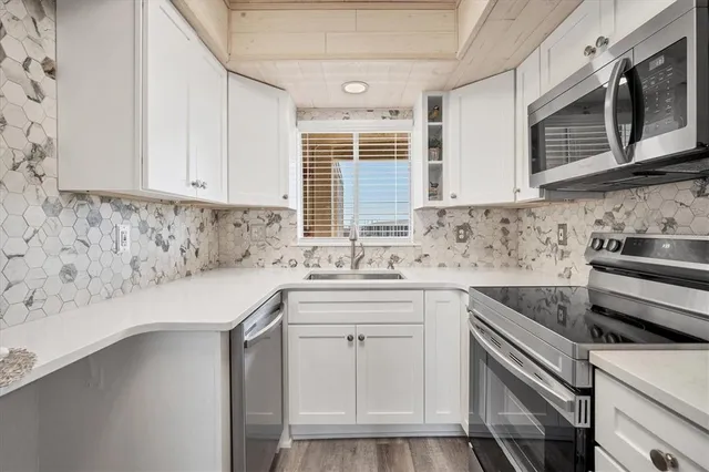 a kitchen with stainless steel appliances granite countertop a sink and cabinets with wooden floor