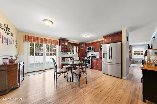 a kitchen with stainless steel appliances a refrigerator a stove a dining table and chairs with wooden floor